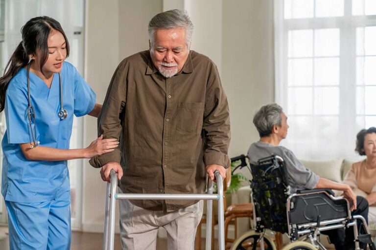 An older adult smiles with family while unpacking boxes in a bright, cozy apartment.